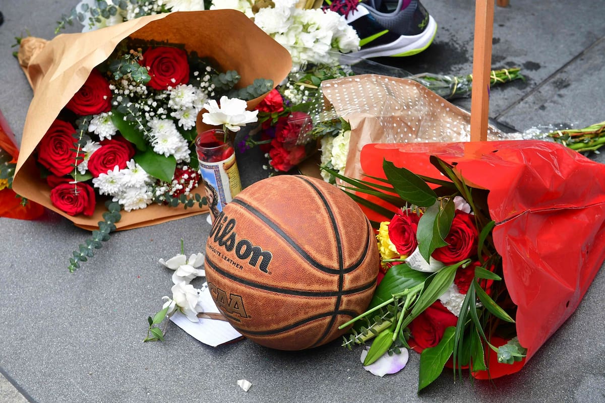 La gente se reúne alrededor de un monumento improvisado para el ex jugador de la NBA y Los Angeles Lakers Kobe Bryant después de enterarse de su muerte en LA Live plaza frente al Staples Center en Los Ángeles