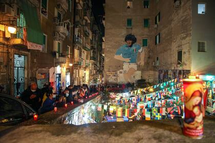 La gente se reúne en la cima del Quartieri Spagnoli en Nápoles junto a un mural de 1990 que representa a la leyenda del fútbol argentino Diego Maradona,