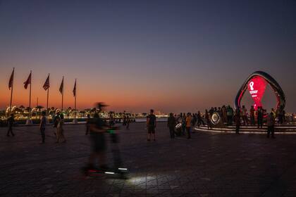 La gente se saca foto en el reloj con la cuenta regresiva del Mundial Qatar 2022, en la Corniche de Doha, el domingo 16 de octubre de 2022. (AP Foto/Nariman El-Mofty)