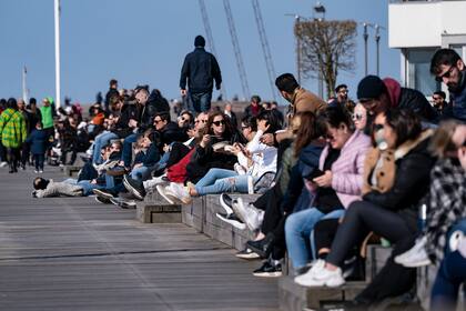 La gente se sienta al sol en el puerto occidental de Malmo, Suecia, el 5 de abril de 2020