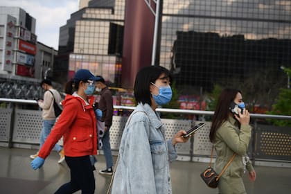 La gente usa barbijos en medio de preocupaciones por el coronavirus mientras caminan afuera de un centro comercial en Pekín el 17 de abril de 2020