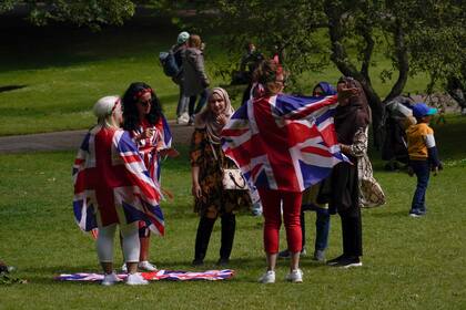La gente viste banderas de la Unión en St James's Park, antes del inicio del fin de semana del Jubileo de la Reina, en Londres, el miércoles 1 de junio de 2022. Gran Bretaña celebrará los 70 años de la reina Isabel II en el trono con cuatro días de festividades que comienzan con su cumpleaños ceremonial desfile el 2 de junio de 2022. (AP Photo/Alberto Pezzali)