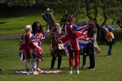 La gente viste banderas de la Unión en St James's Park, antes del inicio del fin de semana del Jubileo de la Reina, en Londres, el miércoles 1 de junio de 2022. Gran Bretaña celebrará los 70 años de la reina Isabel II en el trono con cuatro días de festividades que comienzan con su cumpleaños ceremonial desfile el 2 de junio de 2022. (AP Photo/Alberto Pezzali)