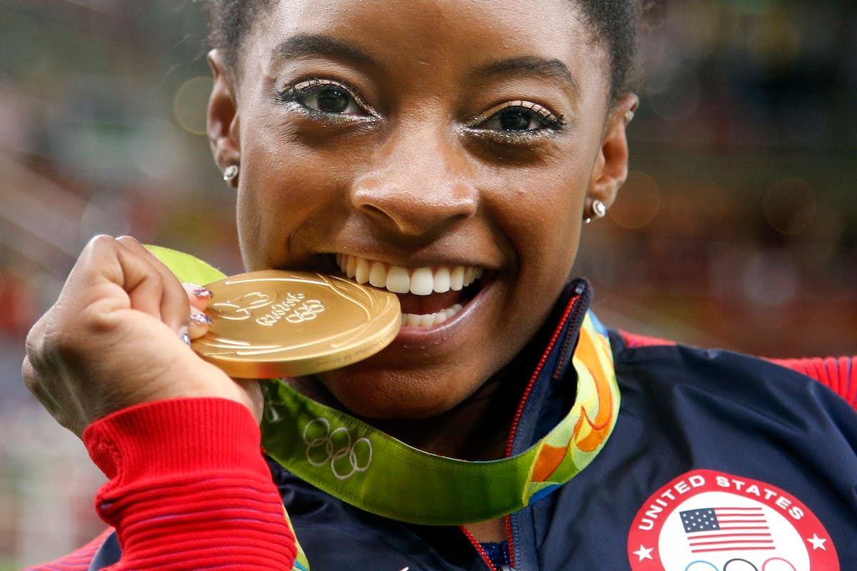 La gimnasta estadounidense Simone Biles muerde su medalla de oro tras ganar la medalla de oro en el concurso completo de los Juegos Olímpicos de Río de Janeiro 2016, el 11 de agosto de 2016. (AP Foto/Dmitri Lovetsky)