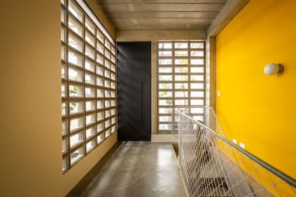 La grilla vidriada y el amarillo potencian el ingreso de luz por este sector de circulación.