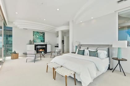 La habitación principal, con una decoración sofisticada en blanco y color agua, está alfombrada y tiene chimenea y terraza.