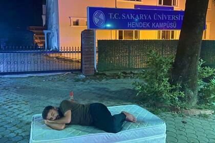 La imagen de un joven durmiendo con colchones en la puerta de la universidad de Sakarya