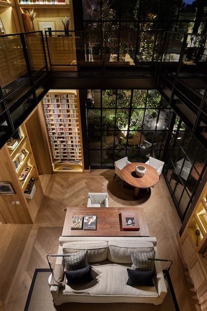 La imponente biblioteca con iluminación led en los estantes crea un ambiente sobrio y sofisticado. El hierro negro es otro sello del arquitecto, un recurso acertado para generar un diálogo entre las diferentes materialidades.