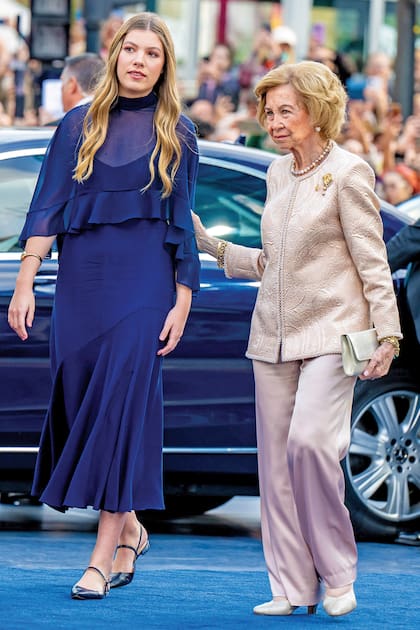 La infanta Sofía –con un vestido azul noche de Miphai, zapatos haciendo juego, un colgante en forma de la Cruz de la Victoria y el anillo de Karen Hallam de su madre–, junto a su abuela, la reina emérita Sofía (con traje sastre bicolor y un broche floral)