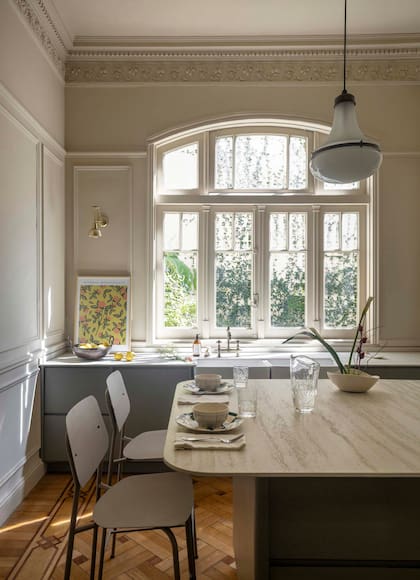 La isla central, casi una mesa, funciona como apoyo auxiliar, y también para comer y trabajar. Banquetas (Estudio Te). En el piso, combinaron listones de roble con nogal para las guardas.