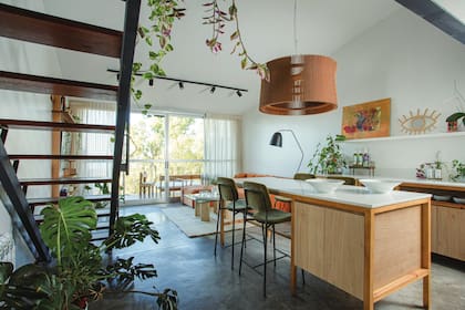 La isla con mesada de cuarzo ‘Calacatta’ y el mueble de madera maciza con frente de melamina ‘Kendal’ (Egger) convirtieron el espacio de comedor en una gran cocina abierta.