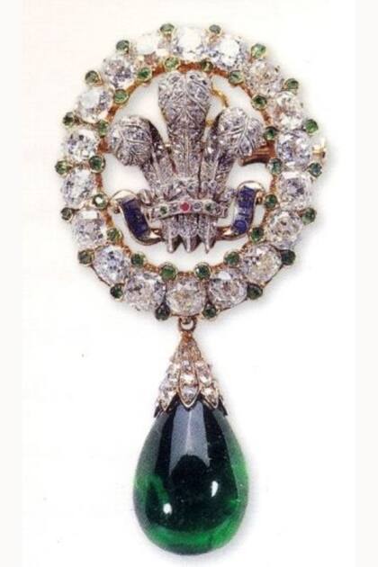 La joya es un óvalo de 18 diamantes con diminutas esmeraldas intermedias, rodeando las tres plumas del Príncipe de Gales en diamante, además, se le incorporó una esmeralda en forma de gota