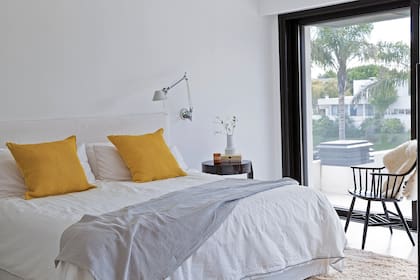 Ropa de cama (Doña Estampas). La lámpara blanca de brazo flexible habilita la lectura nocturna y despeja la mesa de luz.