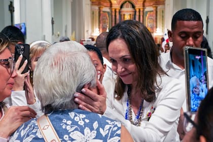 La líder opositora venezolana María Corina Machado sostiene el rostro de una mujer al salir de una misa en la Basílica Nacional Santa María la Antigua, en Ciudad de Panamá