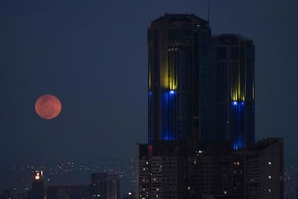 La luna rosa llena sale junto a la torre del Parque Central de Caracas, el 16 de abril de 2022