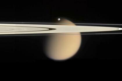La luna Titán (en la imagen detrás de los anillos de Saturno) es la segunda más grande del sistema solar y ahora se conocieron los detalles de su superficie