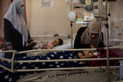 La madre de Yazan Al-zaharna, de 9 años, lo consuela mientras descansa en el hospital Shifa en la ciudad de Gaza, el jueves 13 de mayo de 2021, donde recibe tratamiento por las heridas causadas por un ataque israelí del 10 de mayo que afectó a una familia cercana. casa en la ciudad de Jabaliya. Hace apenas unas semanas, el débil sistema de atención médica de la Franja de Gaza estaba luchando con un aumento desbocado de casos de coronavirus. Ahora, los médicos de todo el abarrotado enclave costero están tratando de mantenerse al día con una crisis muy diferente: heridas por explosiones y metralla, cortes y amputaciones. (Foto AP / Khalil Hamra)