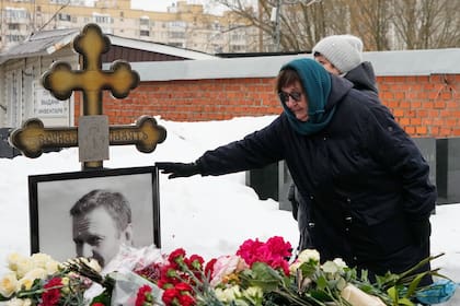 La madre del fallecido líder opositor ruso Alexei Navalny, Lyudmila Navalnaya, toca el retrato de su hijo en su tumba