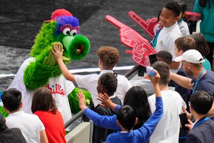La mascota de los Filis saluda a niños mientras el equipo entrena en el London Stadium, el viernes 7 de junio de 2024. Los Mets de Nueva York jugarán en Londres contra los Filis el 8 y 9 de junio. (AP Foto/Kirsty Wigglesworth)