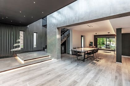 Los escalones avanzan sobre la galería para poder sentarse también allí. Con la buña y la luz, se buscó simular que flotan. La mesa del comedor (Fred), con tapa en Neolith. Sillas (Ananda Design)