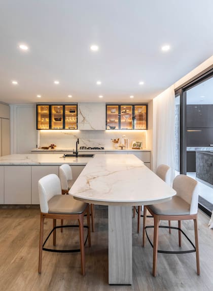 La mesada es en Neolith ‘Abu Dhabi’ (Marmolería Cavatori). La isla, con pie revestido en melamina ‘Kendal’ (Egger) está acompañada por banquetas tapizadas (Sierra).
