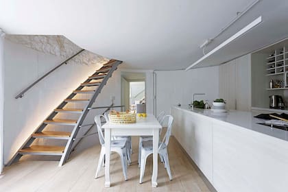La barra (Silestone) tiene un efecto magnético que atrae a los visitantes. Como en living, la escalera de hierro tiene luces.