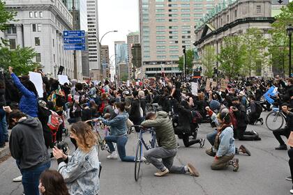La multitud se arrodilla mientras hace un minuto de silencio en memoria de George Floyd, asesinado a manos de la policía de Minnieapolis, durante un mitin en la Place du Canada de Montreal el 31 de mayo de 2020