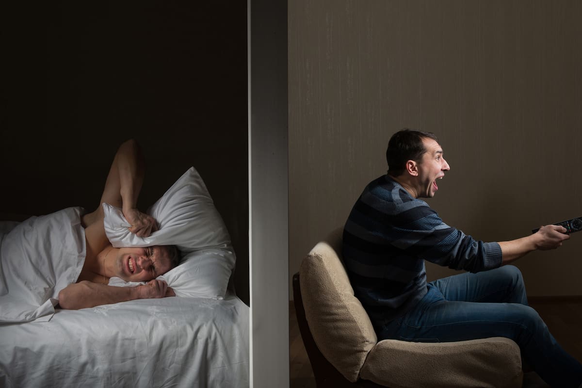 La música alta o los ruidos molestos se categorizan según las disposiciones municipales
Man at night can't fall asleep because of the noisy neighbor