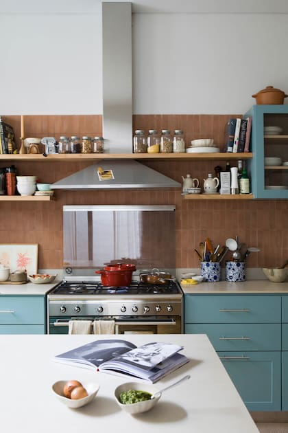La paleta combina el terracota del lindísimo revestimiento de la alzada (Noi Estudio), puesto de modo vertical, como es tendencia, con el celeste de los muebles. En el centro, la mesa de trabajo, que también funciona como desayunador y mesa para comidas más casuales.