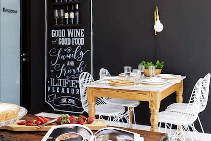 La pared del comedor diario se revistió con pintura de pizarrón y tiene un motivo gráfico (Todo con Tiza) enmarcando los estantes para el vino. Lámpara de pared, mesa con tapa de mármol (ambos, Lodd) y sillas ‘Eiffel’ (desillas.com).