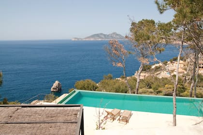 La pileta, revestida con venecitas verdes (FloorTech) y de líneas bien rectas, se funde con el Mediterráneo entre el verde de los pinos.