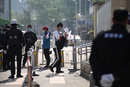 La policía vigila el ingreso de alumnos en una escuela en Pekín; el control sobre la información generó tres detenciones en los últimos días