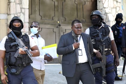 La policía de Direction Centrale de la Police Judiciaire (DCPJ) patrulla el área con forenses, mientras el juez Carl Henry Celestin (C) observa, fuera de la residencia presidencial en Puerto Príncipe, Haití