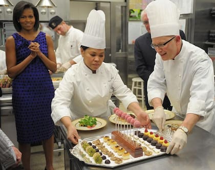 La primera dama Michelle Obama observa a Cristeta Comerford y el chef pastelero William Yosses con los postres para la Cena de los Gobernadores de 2009