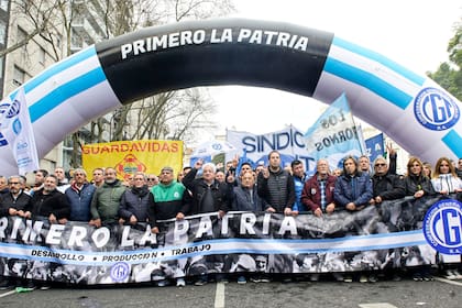 La primera línea de la CGT: Héctor Daer, Carlos Acuña, Pablo Moyano, Julio Piumato, Raúl Durdos, Pablo Flores, Cristian Jerónimo, Omar Plaini y Daniel Ricci sostienen la bandera con la leyenda "Primero la patria"