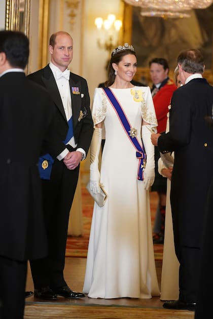 La princesa de Gales, con un diseño de Jenny Packham con bordados de flores en hilo metalizado. Lleva, además, la tiara Strathmore Rose, cuyo diseño permite usarla de dos formas diferentes: sobre la cabeza o sobre la frente, a modo de bandana.