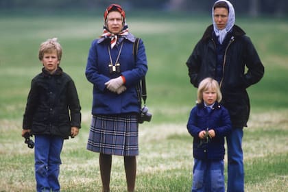 La princesa, en el Windsor Horse Show, en 1985, con sus hijos Peter y Zara y su madre, la reina Isabel. De ella, Ana heredó la pasión por los caballos, los perros, la vida al aire libre y ciertos tips a la hora de vestirse, como los colores y los pañuelos en la cabeza