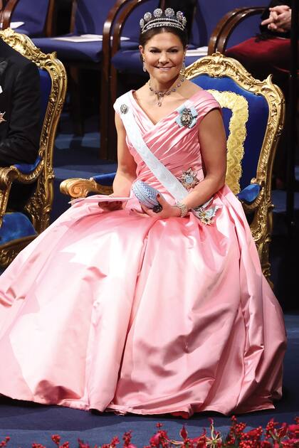La princesa Victoria eligió un traje con falda voluminosa de la diseñadora Camilla Thulin Design. Lo complementó con la tiara de Seis Botones, los pendientes Vasa, creados con diminutos diamantes, y una gargantilla con piedras azules. También llevó un broche con el retrato de su padre, la banda y la estrella de la Orden de los Serafines y un clutch de Bottega Veneta.