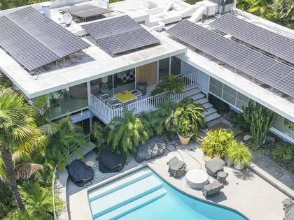La propiedad dispone de un amplio jardín trasero con piscina, rodeada por terrazas y ventanales que conectan con el interior