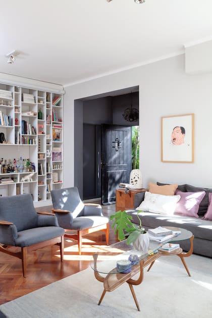 La puerta de entrada cambió de rojo a negro. Sillones individuales estilo Mid Century y mesita escandinava (La Maja Remates). Almohadones (Mercedes Segura).