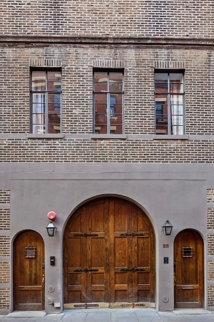La puerta de garaje de madera arqueada con detalles de hierro, uno de los detalles que permite identificarla.
