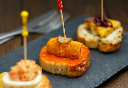La Real Academia Española define la tapa como “porción de alimento que se sirve para acompañar una bebida”