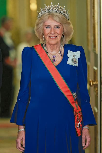 La reina Camilla optó por un vestido azul de Fiona Clare, la tiara Girls of Great Britain and Ireland, un collar de amatistas y la banda roja de la Orden de Omán de Primera Clase, distinción otorgada por el propio sultán