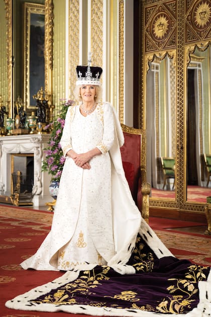 La reina Camilla posa en el salón verde, uno de los más deslumbrantes de Buckingham, con la corona de la reina María de Teck. Por encima del vestido creado por Bruce Oldfield, el manto púrpura pende desde sus hombros y se extiende en el piso en todo su esplendor.