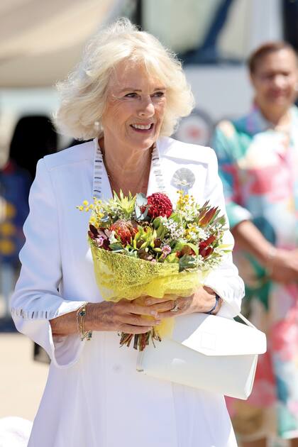 La reina Camilla recibe flores a su llegada a Canberra. Lleva un vestido de crêpe de seda de Anna Valentine.
