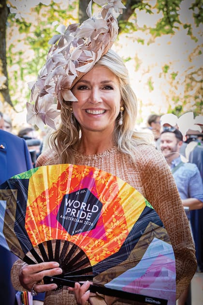 La Reina eligió un vestido semitransparente de alta costura de Natan, de manga larga, cuello a la base, cintura marcada y un original estampado de cuadros, que acompañó con un tocado XXL confeccionado con decenas de hojas de laurel en dorado, de la firma neerlandesa Berry Rutjes
