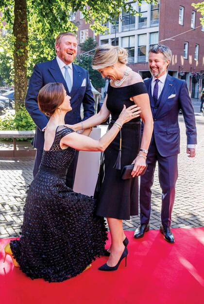 La Reina estrenó un vestido de Carolina Herrera con cinturón tipo soga de cuero, que complementó con stilettos Gianvito Rossi, clutch Bella, collar con broche y varias hileras de perlas; y su reloj Ellipse de Patek Philippe. La princesa heredera danesa, que en la foto se la ve haciendo la reverencia ante Máxima, repitió un vestido de Temperley London y le sumó un clutch de Sergio Rossi, stilettos de Manolo Blahnik, pendientes de oro amarillo y diamantes de Ole Lynggaard y brazalete de Rebekka Notkin.