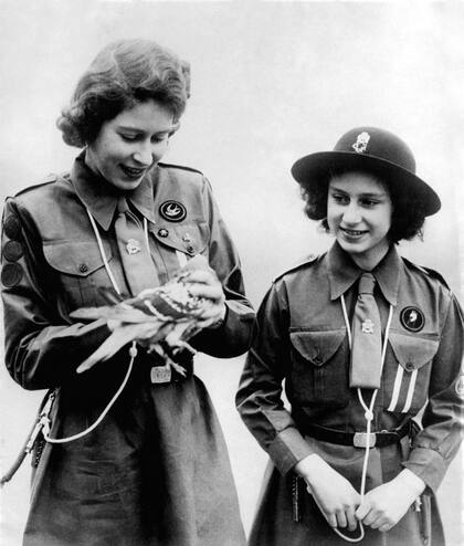 La reina Isabel II, cuando aún era princesa, mostrándole a su hermana Margaret una de las palomas mensajeras.