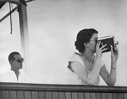 La reina Isabel II filma la llegada del barco de escolta HMNZS Black Prince, mientras se encontraba en el Pacífico Sur en ruta a Fiji, a bordo del SS Gothic durante la gira mundial de coronación, el 11 de diciembre de 1953. A la izquierda está el príncipe Felipe. (Photo by Hulton Archive/Getty Images)
