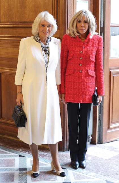 La Reina llevó un equipo de Fiona Clare, que acompañó con cartera y zapatos Chanel, y la primera dama de Francia optó por una chaqueta, también de la mítica firma francesa.